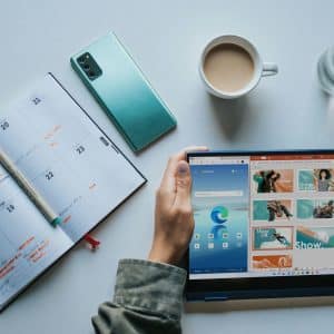 person using Windows 11 computer beside white ceramic mug on white table