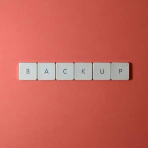 Free Close-up of keyboard keys spelling 'BACKUP' placed on a coral-colored surface. Stock Photo